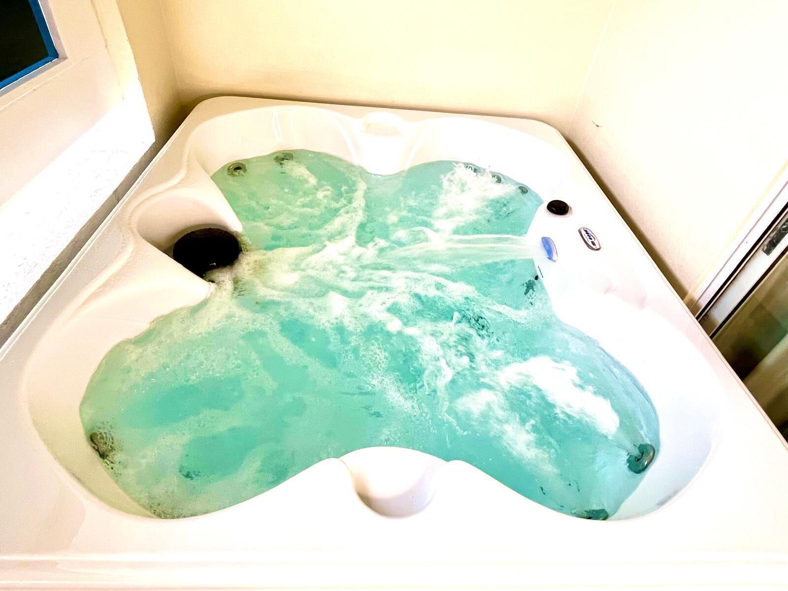 Una vasca da bagno piena d'acqua, un soffione manuale e un pannello di controllo.
