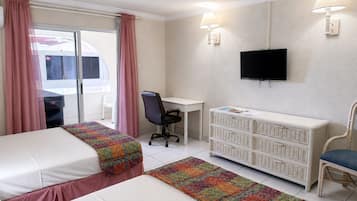 Habitación de hotel con dos camas, un escritorio, una silla, un televisor y una ventana con cortinas.