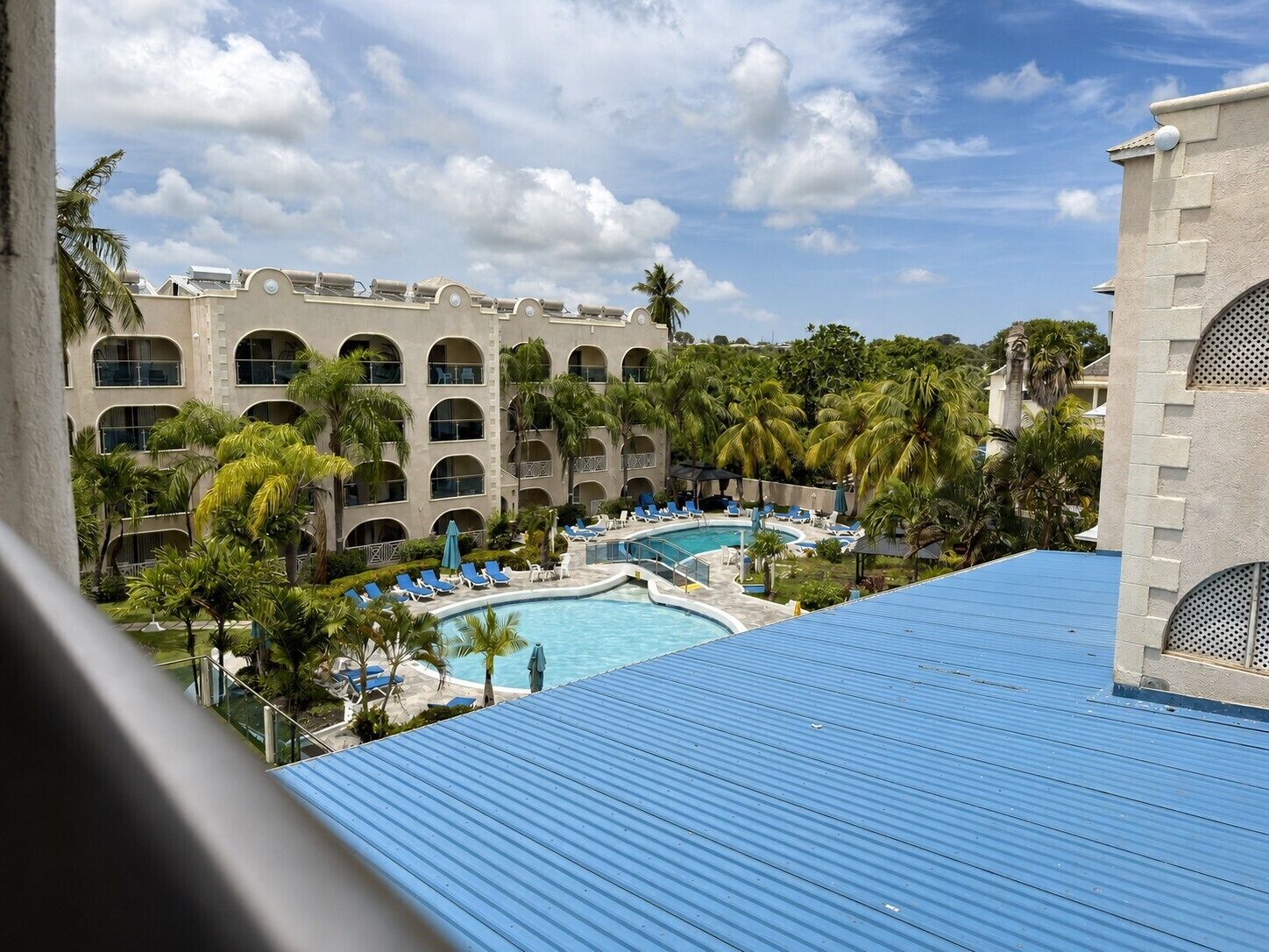 A hotel with a swimming pool surrounded by palm trees and lounge chairs.