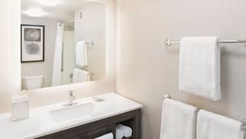 A modern bathroom with a white sink, dark vanity, and a towel rack with multiple towels.