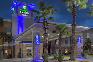 A Holiday Inn Express & Suites building with a covered entrance, palm trees, and a blue-lit sign. - Holiday Inn Express & Suites Fleming Island by IHG (Fleming Island)