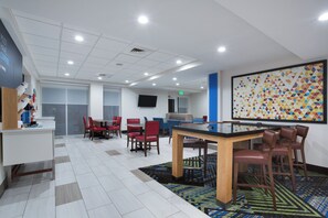 Ein modernes Interieur mit einer Rezeption, einer Sitzecke und einem großen, an der Wand montierten Bildschirm.