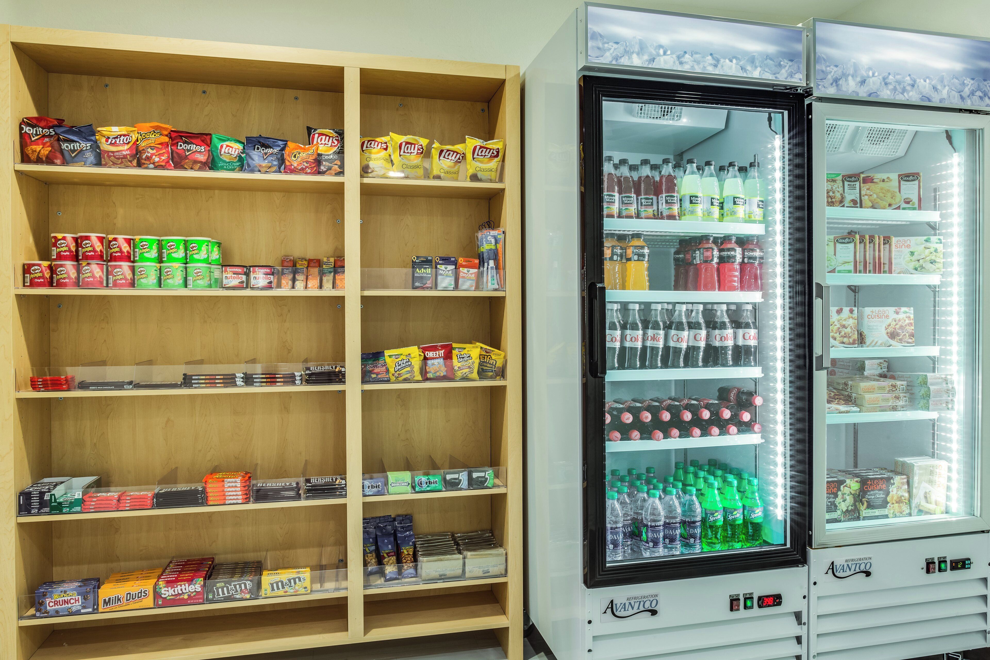 Ein Automaten steht voll mit verschiedenen Snacks und Getränken, darunter Chips, Nüsse und Limonaden.