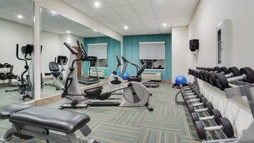 Un gimnasio con diversos equipos de ejercicio, como cintas de correr, bicicletas estáticas y máquinas de pesas.