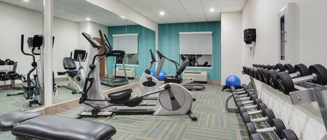 A gym with various exercise equipment, including treadmills, stationary bikes, and weight machines.
