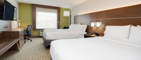 A hotel room with two beds, a desk, a chair, a TV, and a window.