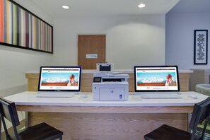 A reception desk with two laptops displaying a hotel website, a printer, and a sign indicating a mechanical room. - Holiday Inn Express & Suites Fleming Island by IHG (Fleming Island)