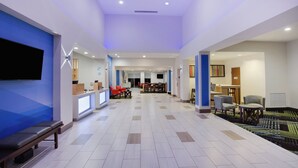 A hotel lobby with a reception desk, seating area, and a television. - Holiday Inn Express & Suites Fleming Island by IHG (Fleming Island)