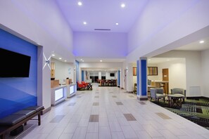 Un hall d’hôtel comprenant un comptoir d’accueil, un espace salon et un téléviseur.
