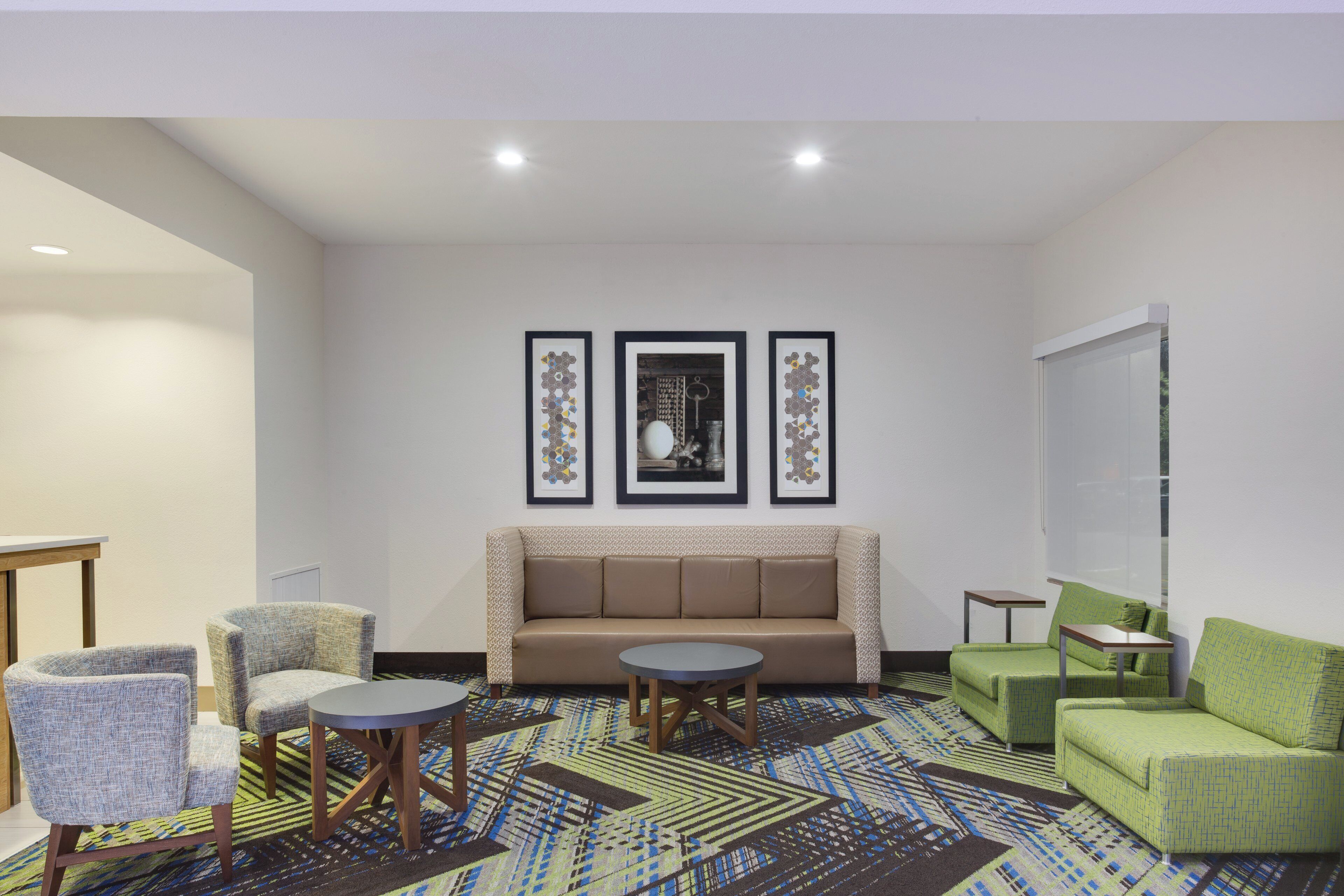 A modern lounge area with a sofa, two armchairs, a coffee table, and a patterned carpet.
