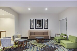 Un salon moderne comprenant un canapé, deux fauteuils, une table basse et un tapis à motifs.
