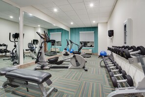 Une salle de sport équipée de machines de cardio, de bancs de musculation et d’haltères.
