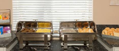 Un buffet con diversi cibi, tra cui carni e dolci, su un piano di lavoro in granito.