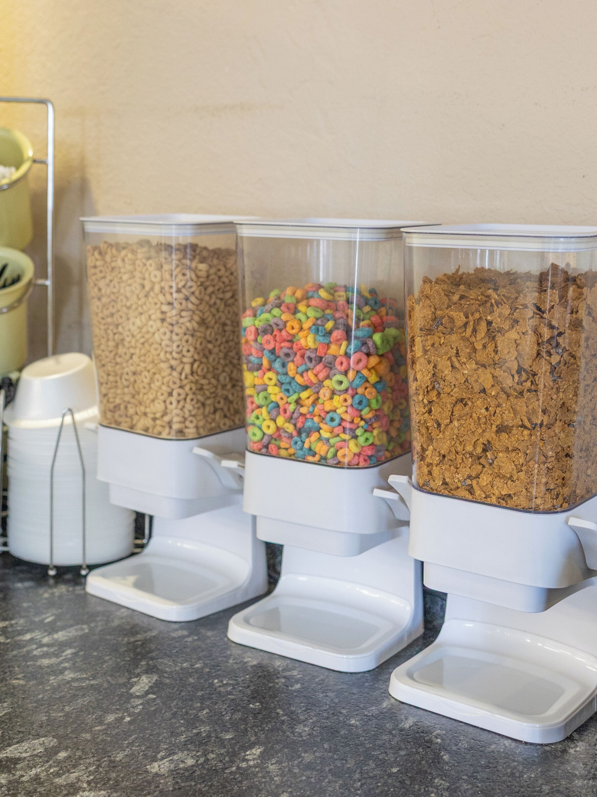 Tres dispensadores en una encimera con distintos tipos de cereal.