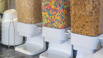 Three dispensers on a countertop with different types of cereal.