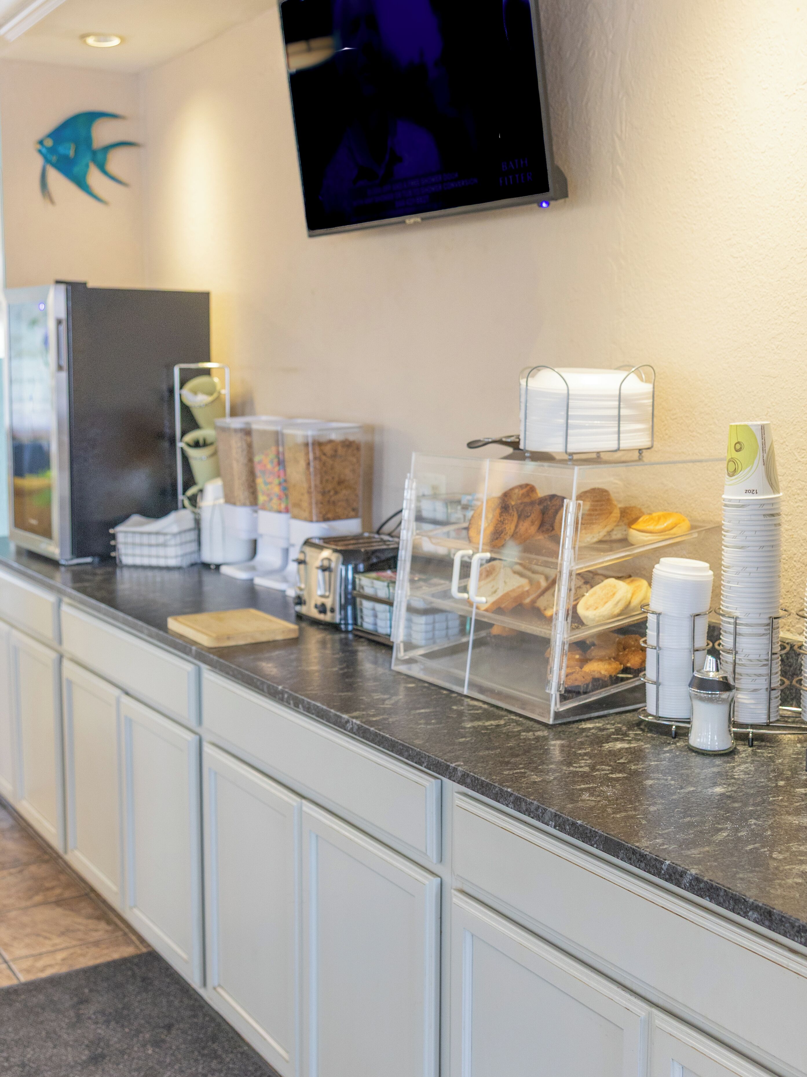 Eine Frühstückstheke mit Kaffeemaschine, einem Kühlschrank und einem an der Wand montierten Fernseher.