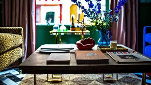 Una mesa de centro de madera con libros, un tazón rojo y un florero con flores azules.