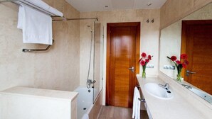 Un baño moderno con bañera, ducha, lavamanos y un espejo grande.