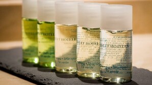Four bottles of hotel shampoo on a black surface. - Leflet Valme (Dos Hermanas)
