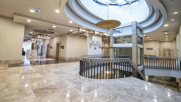 A spacious lobby with a central staircase, a skylight, and a modern chandelier. - Dedeman Konya Hotel And Convention Center (Konya)