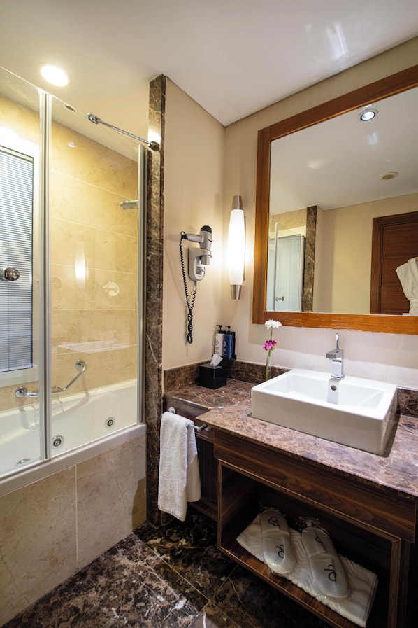 A bathroom with a glass-enclosed shower, a sink, a mirror, and a towel rack. - Dedeman Konya Hotel And Convention Center (Konya)
