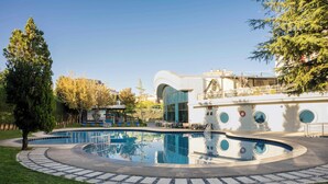 A modern building with a swimming pool, a circular deck, and a grassy area. - Dedeman Konya Hotel And Convention Center (Konya)