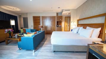 A hotel room with a bed, a sofa, a TV, a desk, and a wardrobe.