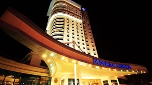 A hotel with a curved facade, illuminated signage, and a prominent entrance. - Dedeman Konya Hotel And Convention Center (Konya)