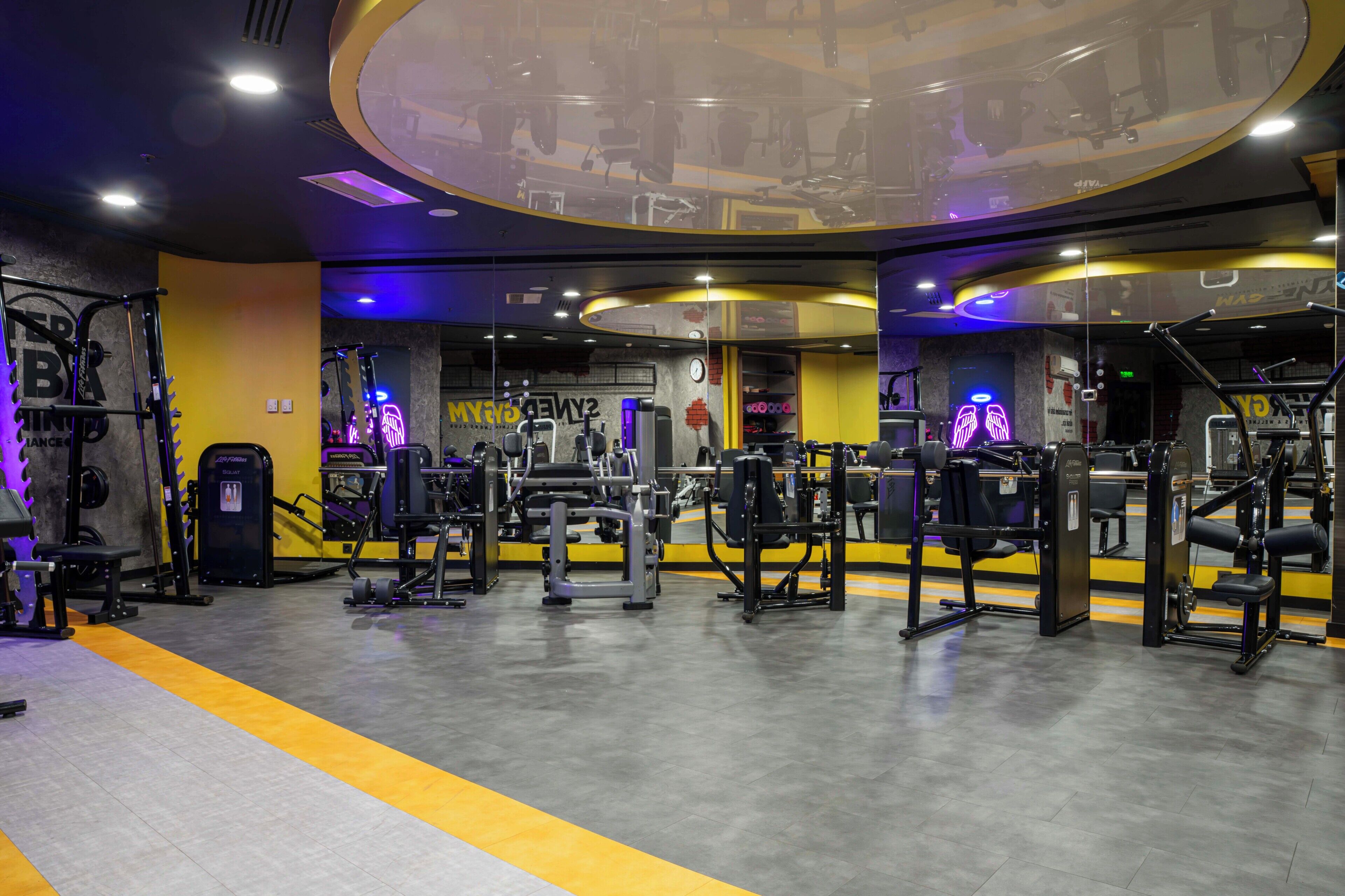 A gym with exercise equipment, mirrors, and a yellow and black color scheme.