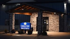 A Cobblestone Inn & Suites building entrance with a stone facade, a covered patio area, and a signboard. - Cobblestone Inn & Suites - Trenton (Trenton)