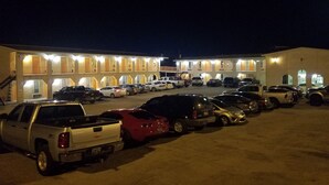 Un motel doté de nombreuses places de stationnement et d’une rangée de chambres dont les fenêtres sont illuminées.