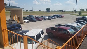 Un parking contenant plusieurs véhicules, notamment des voitures et des camions, et un bâtiment doté d’une zone abritée.