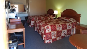 Une chambre d’hôtel avec deux lits, un bureau, une chaise, une petite table et un coin cuisine.