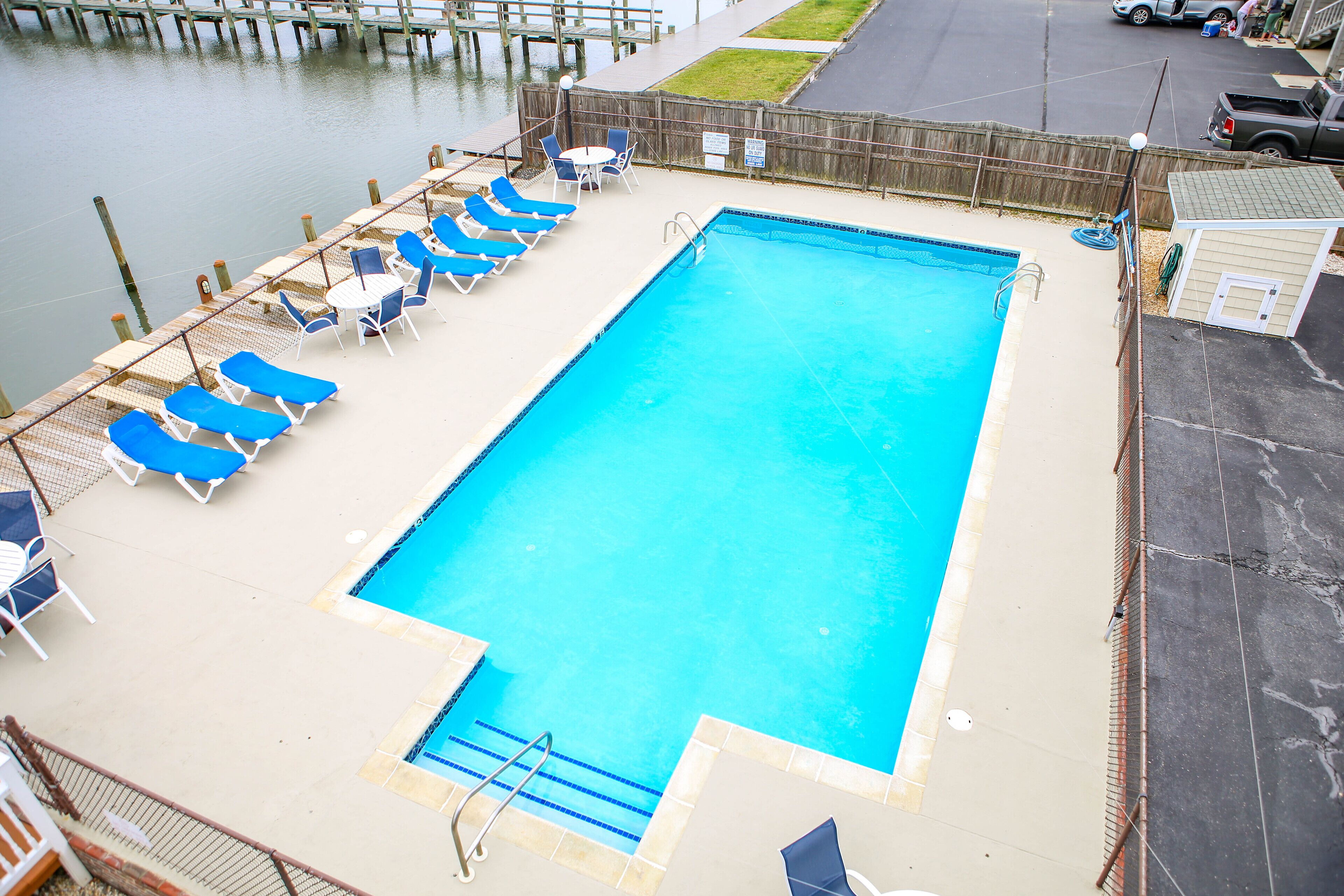 Une piscine rectangulaire à l’eau bleue, entourée de chaises longues et d’une terrasse en bois.