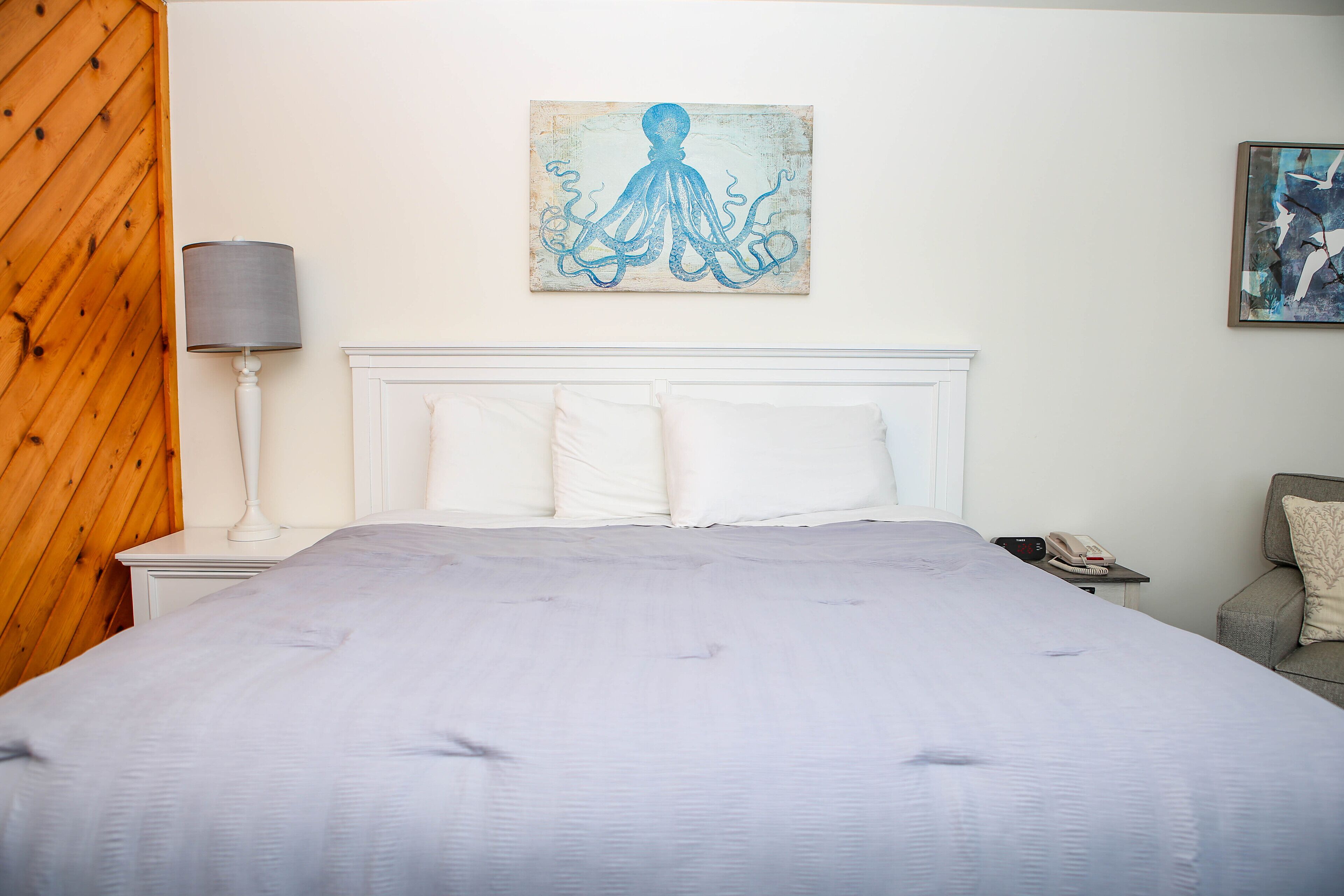 Una camera da letto con un letto grande, una lampada da comodino, un telefono e opere d'arte alle pareti.