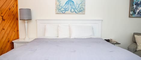 Una camera da letto con un letto grande, una lampada da comodino, un telefono e opere d'arte alle pareti.