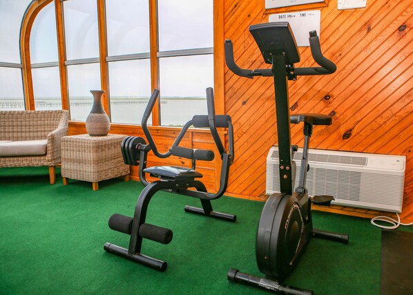 A gym with exercise equipment, a wicker sofa, and a large window with a view.