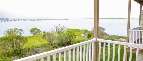 A balcony with a view of a calm body of water and a pier in the distance.