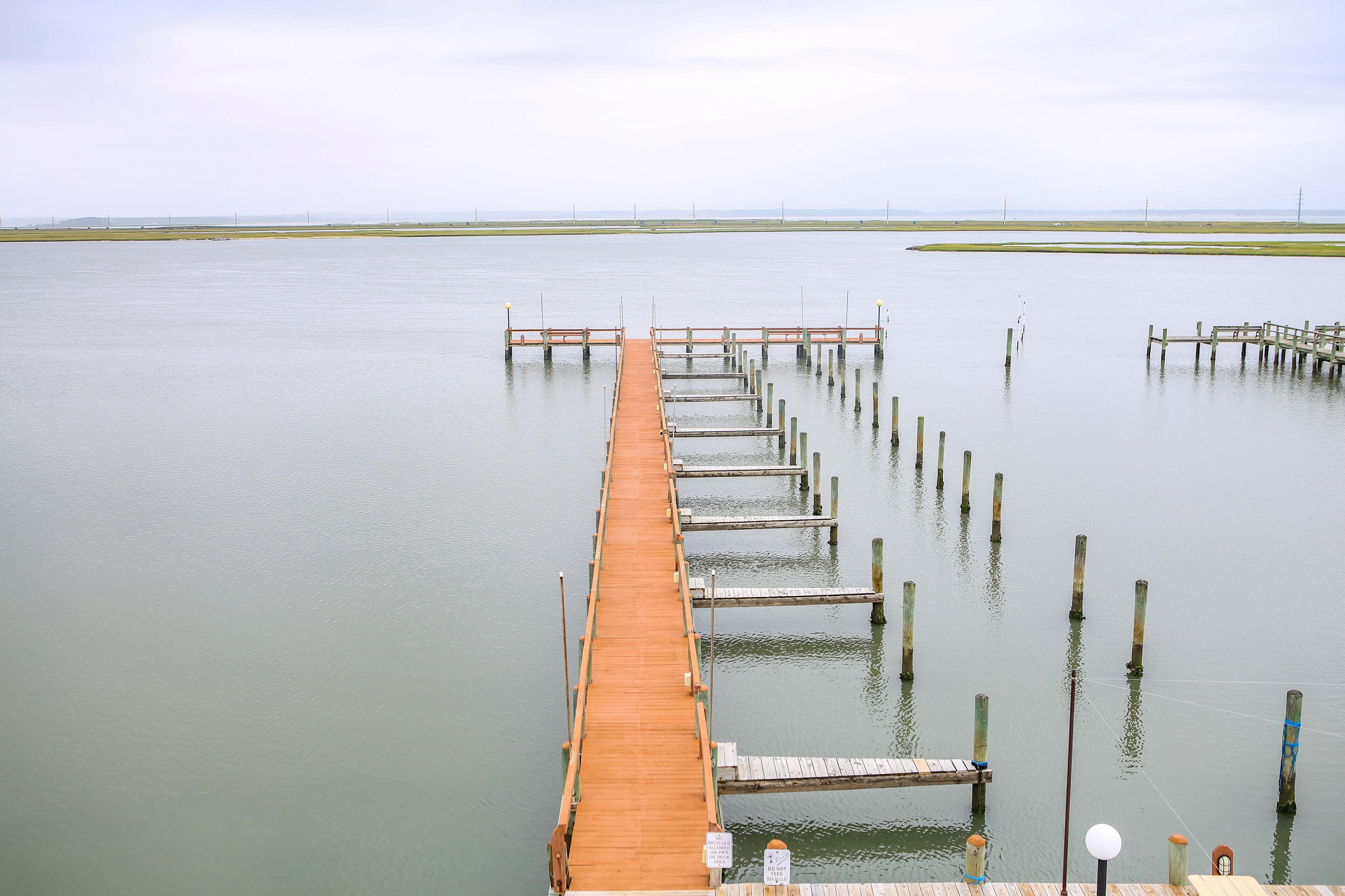 A wooden pier extending into calm water with a clear sky.