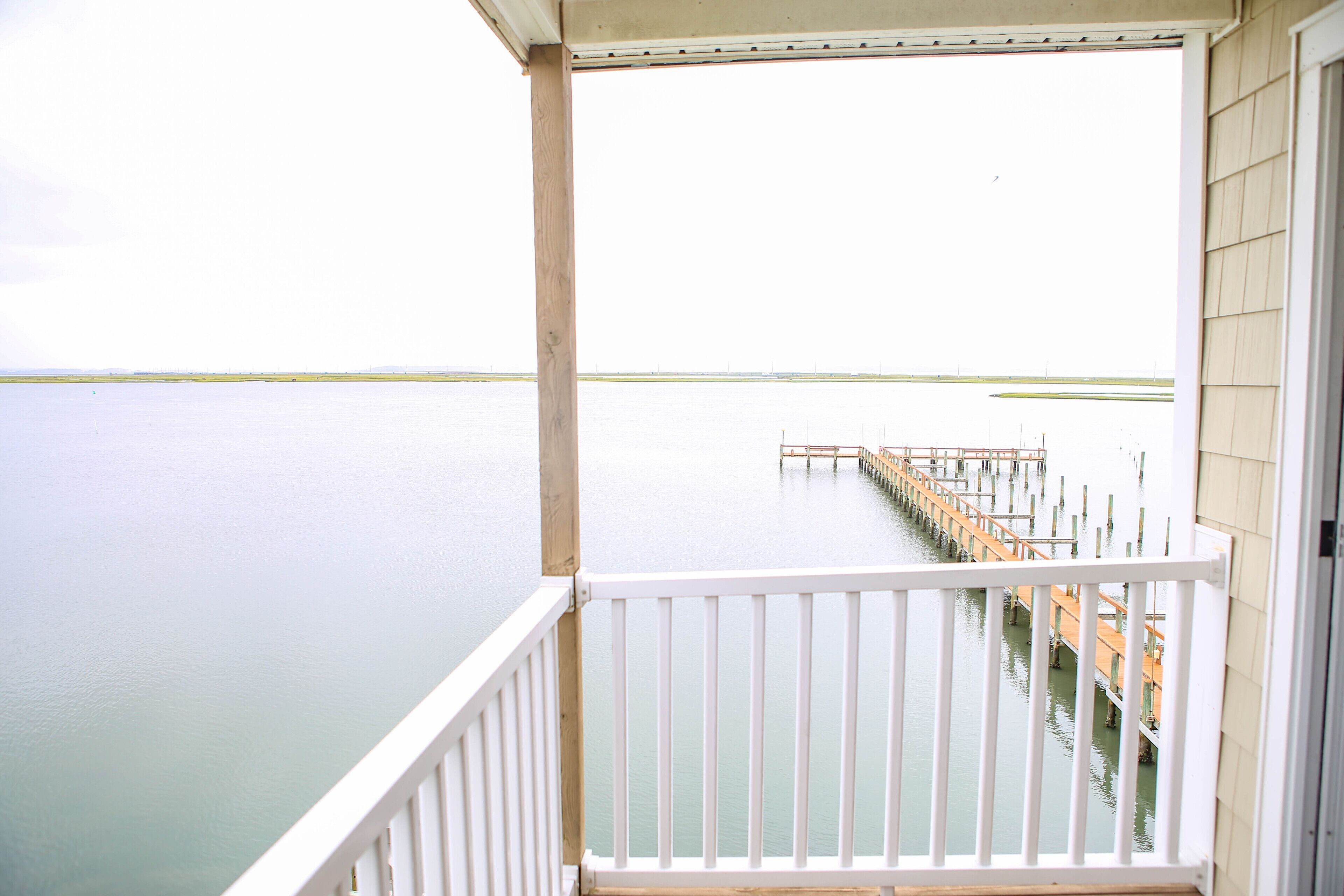 Un balcon donnant sur une étendue d’eau calme et une jetée qui s’avance vers l’horizon.