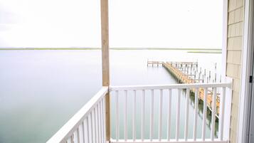 Un balcon donnant sur une étendue d’eau calme et une jetée qui s’avance vers l’horizon.