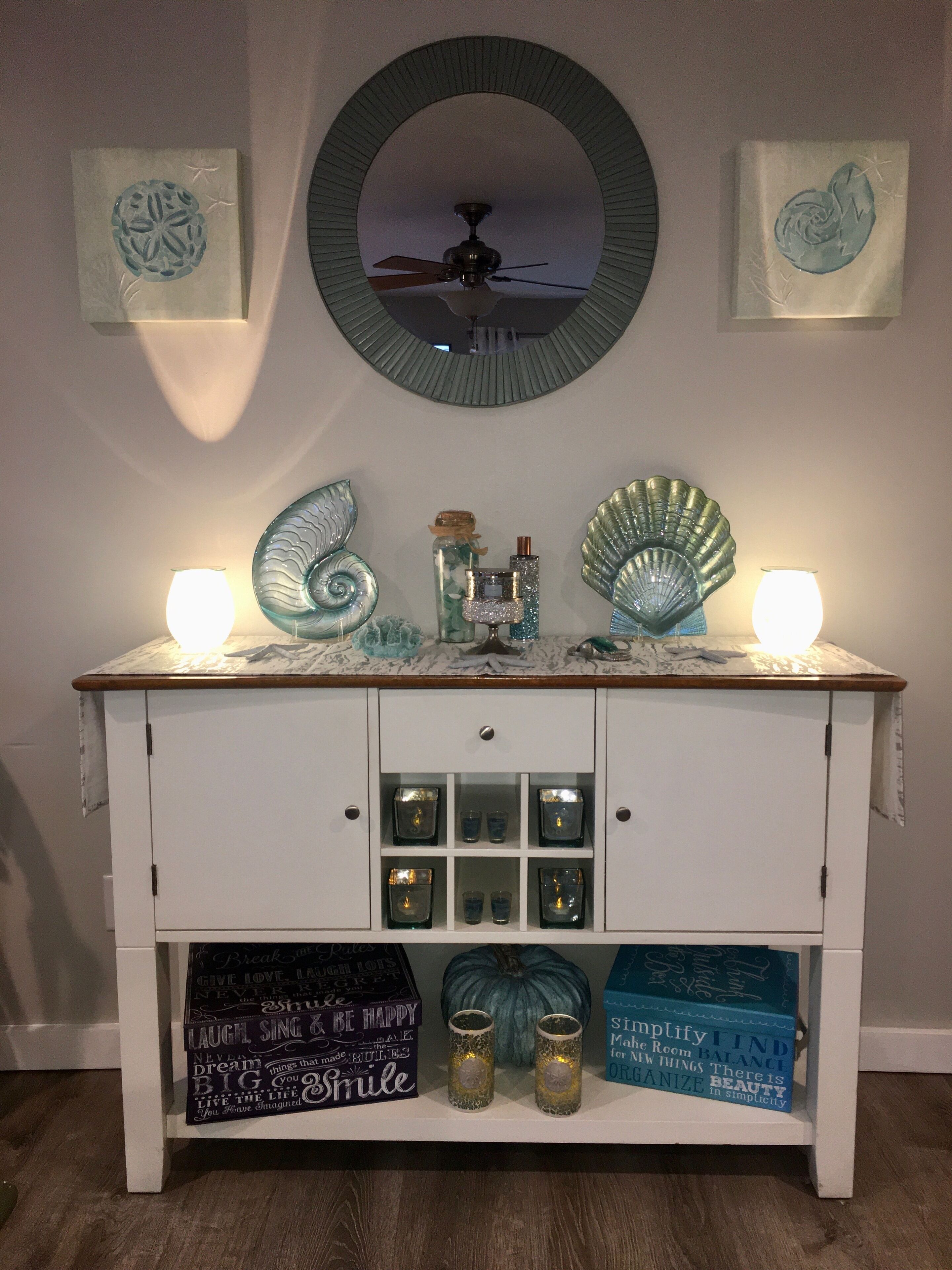 A white cabinet with a mirror above it, shelves with candles, and decorative items.