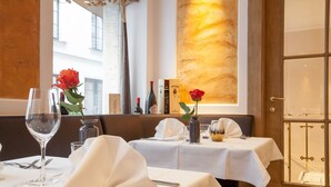 Un comedor con mesas dispuestas para dos, con manteles blancos y copas de vino.