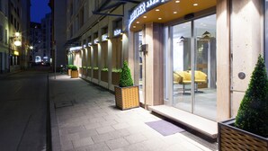 Un hotel con fachada moderna, amplias ventanas y mesas al aire libre.