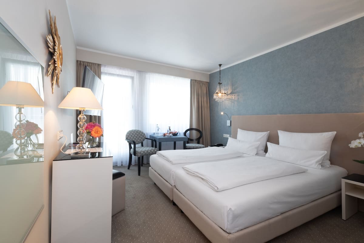 A hotel room with a large bed, a desk, a chair, and a TV.