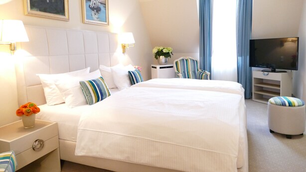 A hotel room with a large bed, two bedside tables, a TV, a desk, and a chair. - Hotel an der Oper (Munich)