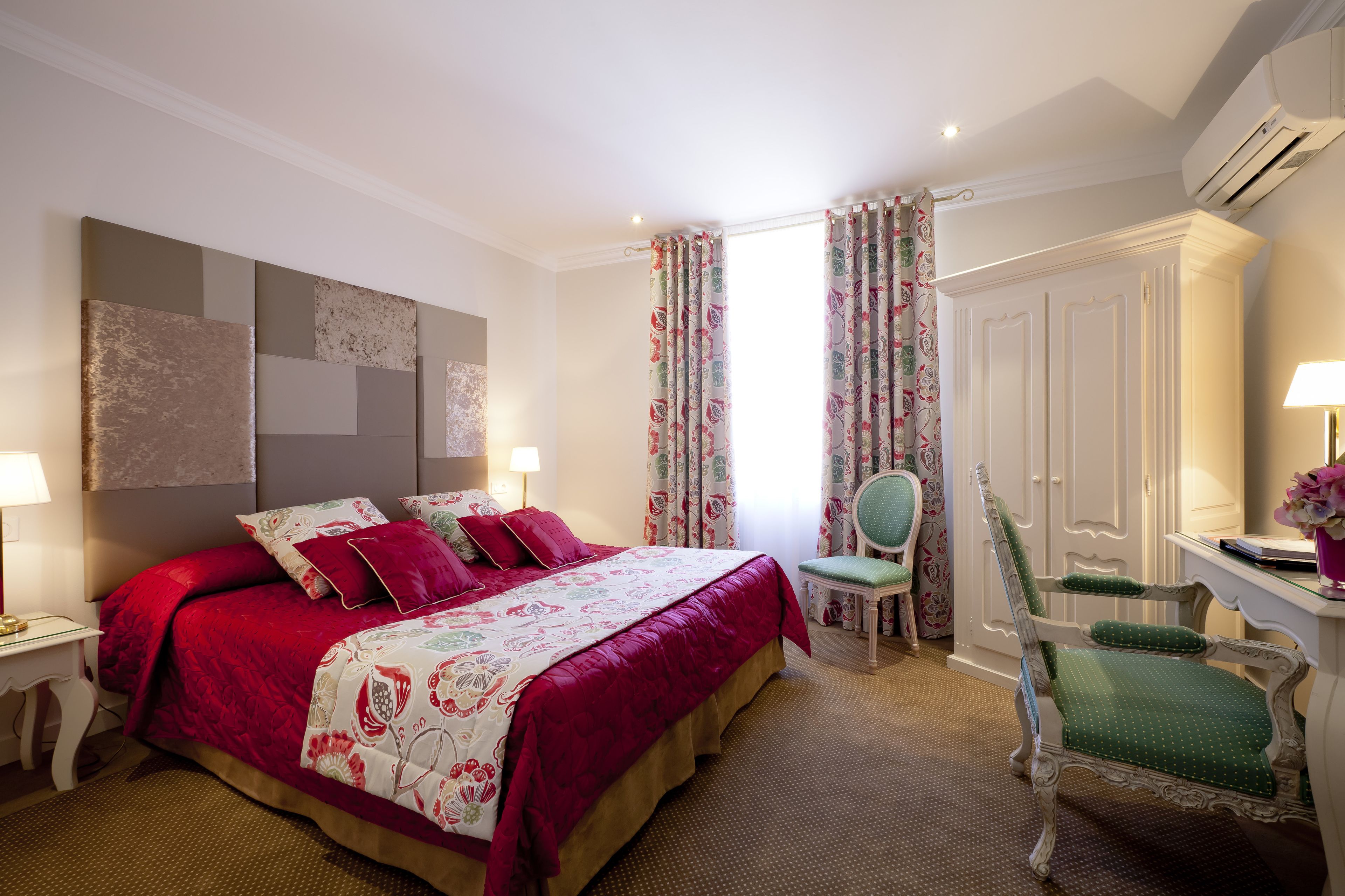 A bedroom with a large bed, a desk, a chair, and a wardrobe.