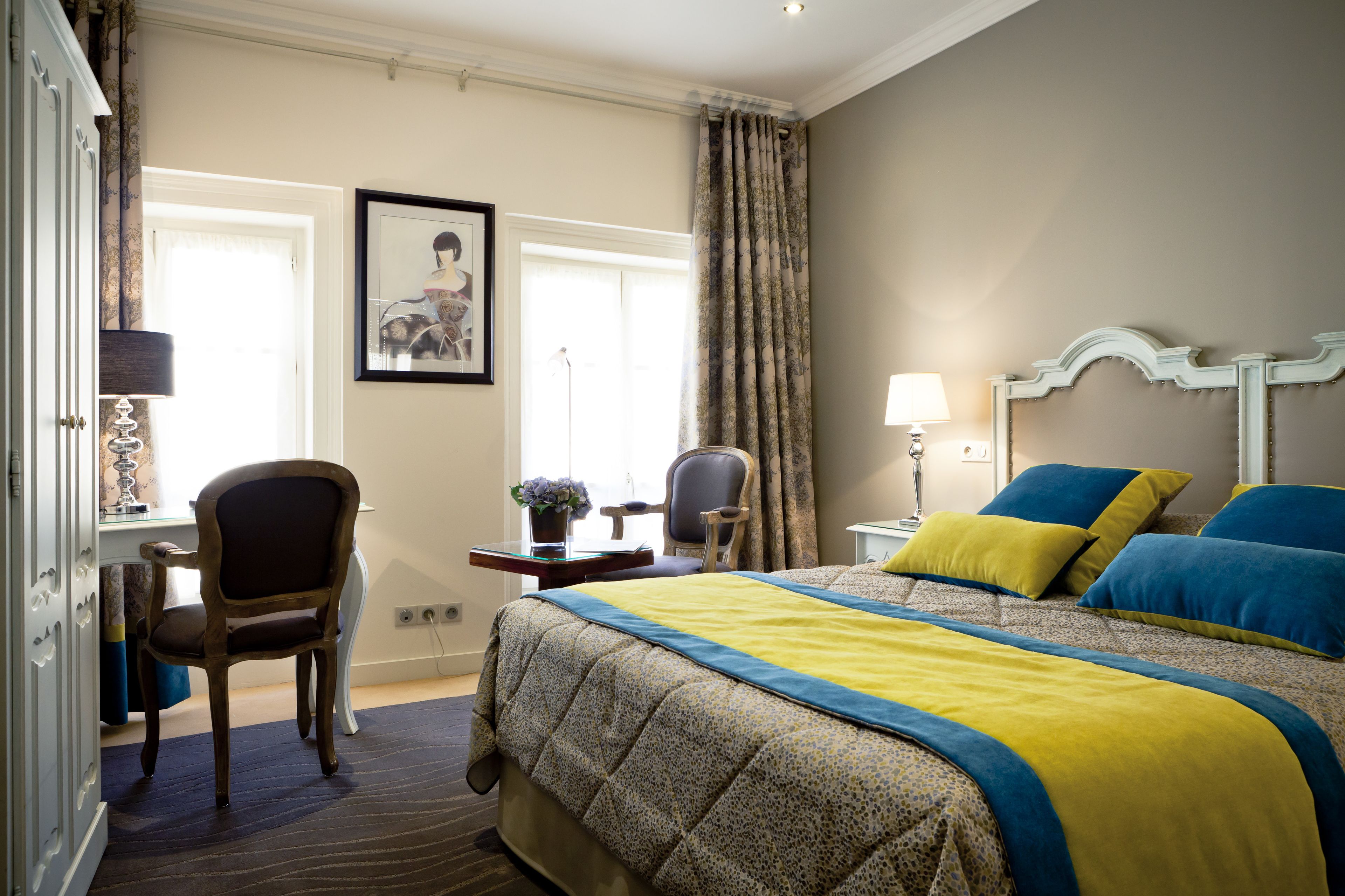 A hotel room with a bed, a desk, a chair, and a window.