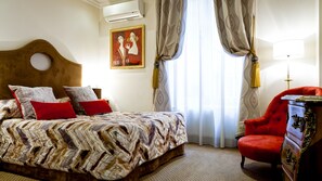 A hotel room with a bed, a red armchair, a wooden headboard, a painting on the wall, and a window with curtains. - Grand Hotel Des Terreaux (Lyon)