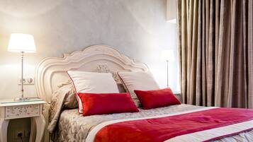A neatly made bed with a white headboard, red and white pillows, and a red and white bedspread. There are two bedside tables with lamps and a small decorative item on one.